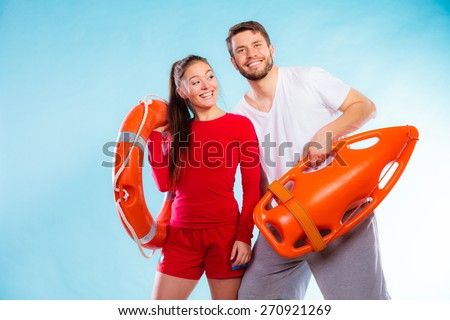 Accident prevention and water rescue. Young man and woman lifeguard couple on duty holding buoy lifesaver equipment on blue