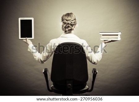Ebook vs book. Woman sitting on chair holding traditional book and e-book reader tablet touchpad pc back view grunge background.