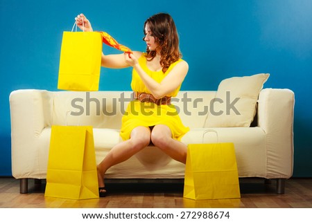Buying retail sale concept. Fashionable girl summer dress high heels sitting on couch with shopping bags on blue