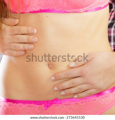 Closeup part of beauty female body, girl in pink lace lingerie. Fit and slim young woman belly with hands on it