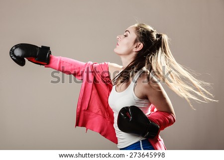 Feminist and emancipation idea. Woman in male occupation, training, boxing. Fit female fitness girl doing exercise on grey background.