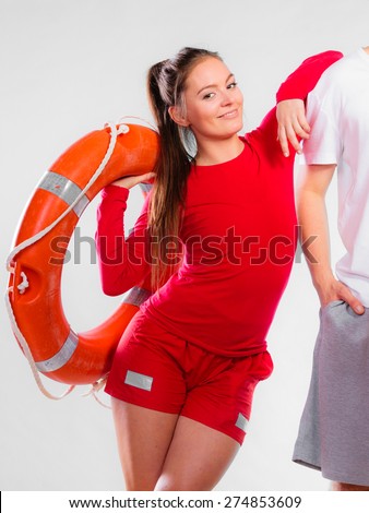 Accident prevention and water rescue. Young woman female smiling lifeguard on duty leaning on male arm holding lifesaver equipment on gray