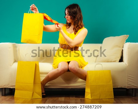 Buying retail sale concept. Fashionable girl summer dress high heels sitting on couch with shopping bags on green