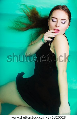 Sensuality and sexuality of women. Sexual posing woman in black dress in water. Indoor.