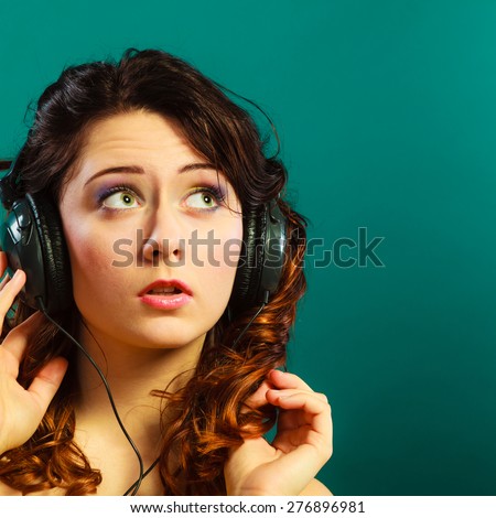 Young people leisure relax concept. Closeup teen cute girl in big headphones listening music mp3 relaxing on green blue background