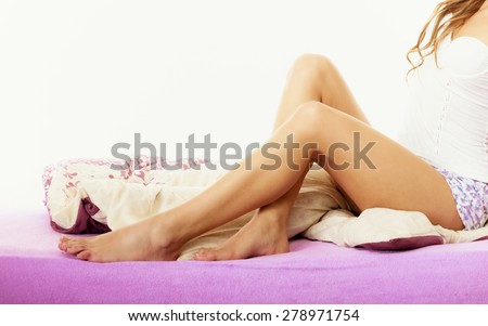 Health and beauty concept. Part of body female legs in bed, woman relaxing waking up