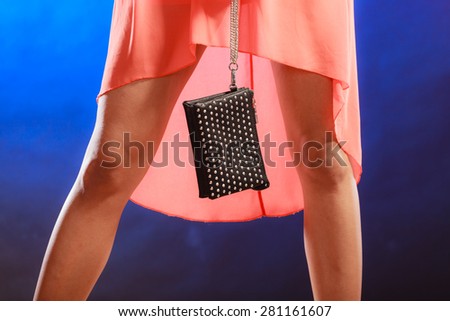Celebration disco and evening fashion concept - woman in orange dress holding handbag bag, dancing in the club, part of body female legs on dark blue