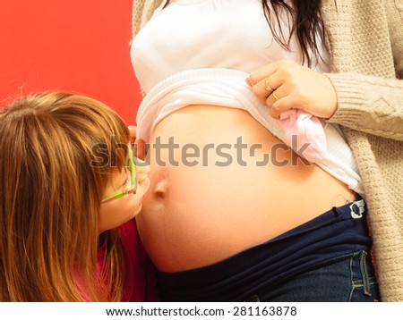 Pregnancy, motherhood and happiness concept. pregnant woman awaiting her second child, little cute girl kissing belly of her mom