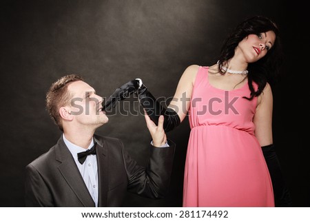 Date. Gallant man in suit and woman in evening dress on black grey background in studio.