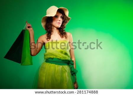 Spring girl young woman holding green paper shopping bags on green. Blank copy space. Sale and retail. Studio shot.