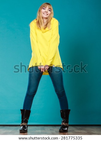Fashion. Full body blonde fashionable woman jeans pants yellow blouse winter boots on blue