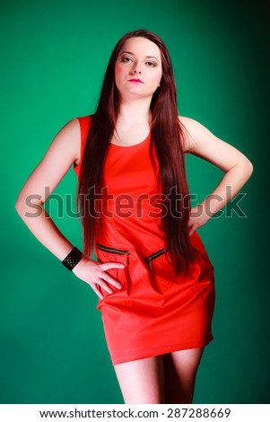 Party, celebration and date concept. Attractive young log hair woman in red dress on green background. Studio shot.