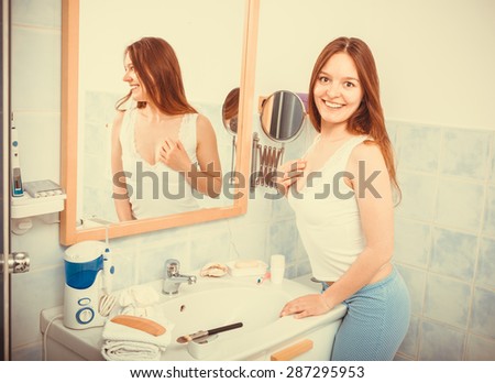 Happy young girl woman without makeup in bathroom standing in front of mirror smiling. Natural beauty. Purity. Instagram filtered.