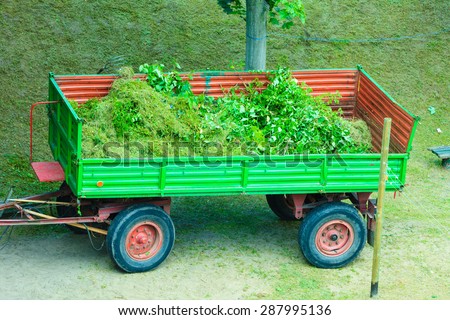Works in public park. Tractor - trailer with tree branches. Environment cleaning concept