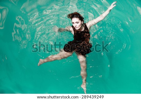Sensuality and sexuality of women. Sexual posing woman in black dress in water. Indoor.