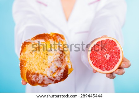 Make the right dietary choice concept. Nutritionist comparing diets options, holding cake sweet food and grapefruit on blue