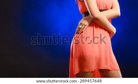 Party clothing evening fashion concept - attractive fashion woman, mixed race girl in orange elegant dress part of body hips dark blue background