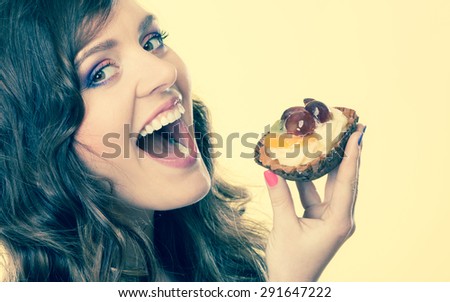 Sweetness and happiness concept. Closeup cute woman curly hair eating fruit cake cupcake face profile yellow background