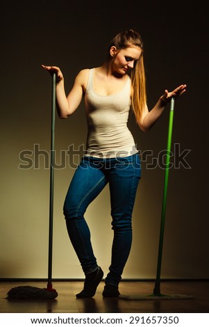 Cleanup housework concept. Funny cleaning lady young woman mopping floor, holding two mops new and old dark background