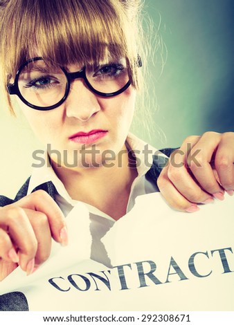 Business, documents and legal concept - serious unhappy businesswoman tearing crumpled contract