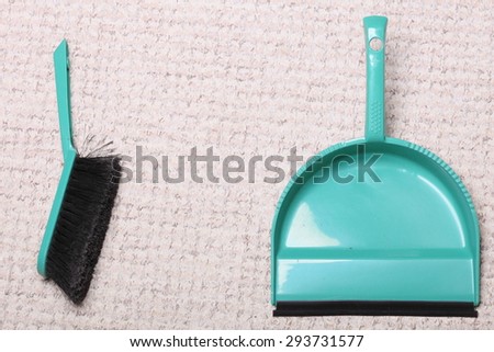 Green sweeping brush and dustpan for house work on floor indoors. Cleaning