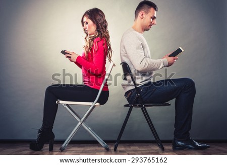 Couple using mobile phones not talking to each other. Unhappy frustrated man and woman use new technology and grow apart.
