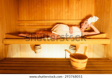 Spa beauty well being and resort concept. Woman in full length white towel lying relaxed in wooden finnish sauna