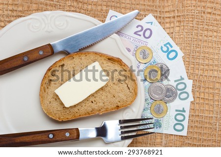 Cost of living, price of eating food budget concept. Polish money on kitchen table, piece of bread on plate