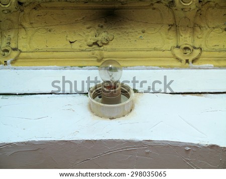 Damaged yellow ceiling and electrical lamp in an old abandoned home