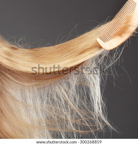 Haircare concept. Closeup straight blonde hair with wooden comb