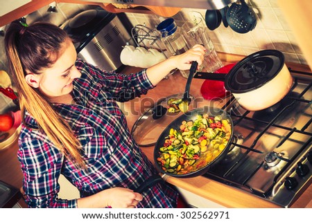 Woman in kitchen cooking stir fry frozen vegetables. Girl frying making delicious dinner food meal. Instagram filtered.