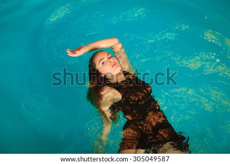 Woman relaxing at swimming pool. Young girl floating. Water aerobics fitness.
