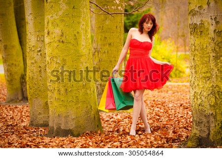 Retail and sale concept. Elegant autumn shopper woman with sale bags outdoor in park after shopping.