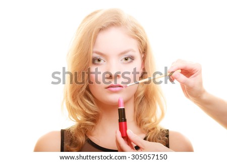 Cosmetic beauty procedures and makeover concept. Makeup artist applying lipstick with accessories tools to woman lips. Isolated studio shot