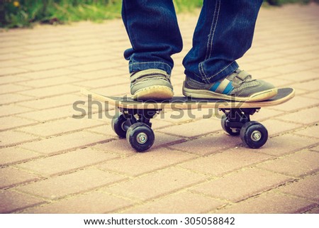 Closeup of skateboarder legs. Kid child riding skateboard outdoor. Active boy skateboarding on pavement sidewalk. Kid practicing outside.