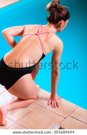 Sport active lifestyle. Sporty woman female swimmer muscular fit body preparing to jumping and diving into swimming pool  back view