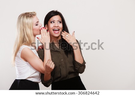 Relationship gossip. Two women multiethnic whispering secret surprised face expression, studio shot