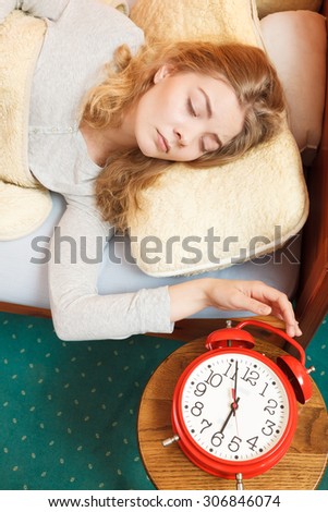 Exhausted woman waking up in bed turning off alarm clock. Young girl in the morning.