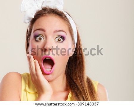 Amazed surprised pin up girl with mouth wide open. Portrait of astonished young woman with bow.