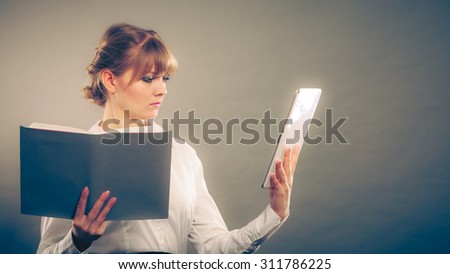 Woman learning with ebook reader and book. Choice between modern educational technology and traditional way method. Girl holding digital tablet and textbook. Contemporary education. Instagram filter.