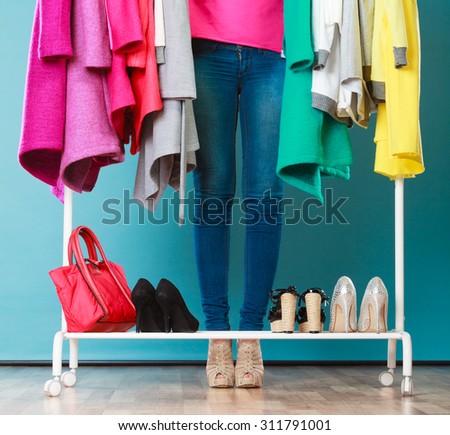 Closeup of woman choosing clothes to wear in wardrobe. Girl customer shopping in mall shop. Fashion clothing sale concept.