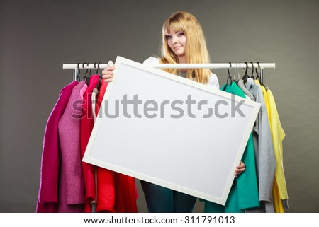 Pretty woman in wardrobe holding blank empty banner. Gorgeous girl customer in mall shop with copyspace. Fashion clothing sale advertisement concept.