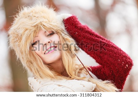 Portrait of pretty smiling fashionable woman in fall forest park. Happy gorgeous young girl in fur winter hat and sweater pullover. Autumn fashion.