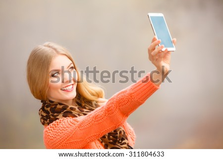 Technology internet and happiness concept. Woman content girl taking self picture selfie with smartphone camera while walking outdoors in autumn park in foggy day
