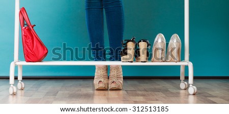 Closeup of woman in high heels choosing shoes to wear in wardrobe. Girl customer shopping in mall shop. Fashion clothing sale concept.