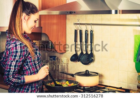 Woman in kitchen cooking stir fry frozen vegetables. Girl frying making delicious risotto. Dinner food meal. Instagram filtered.