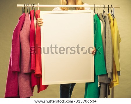 Woman in wardrobe holding blank empty banner. Girl customer in mall shop with copyspace. Fashion clothing sale advertisement.
