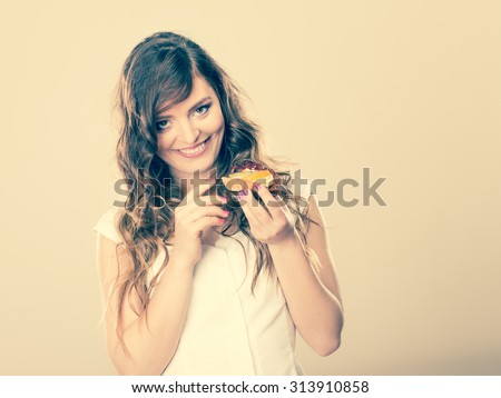 Bakery, sweet food and people concept. cute woman curly hair holding fruit cake cupcake in hand