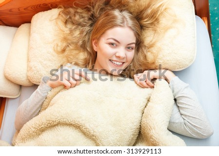Woman waking up in bed in the morning after sleeping. Young girl laying under wool blanket.
