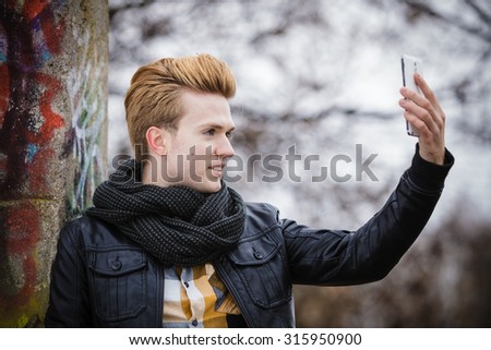 Technology internet and happiness concept. Fashionable guy taking self picture selfie with smartphone camera while walking outdoors foggy day